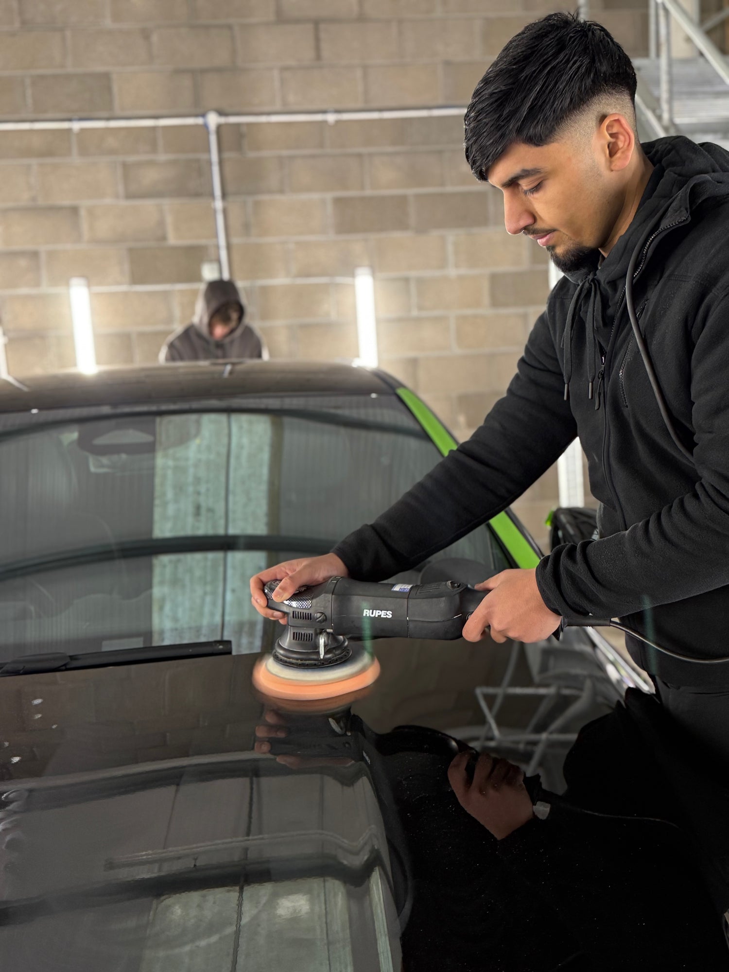 Student/trainee carrying out hands on detailing paint correction a real vehicle.
